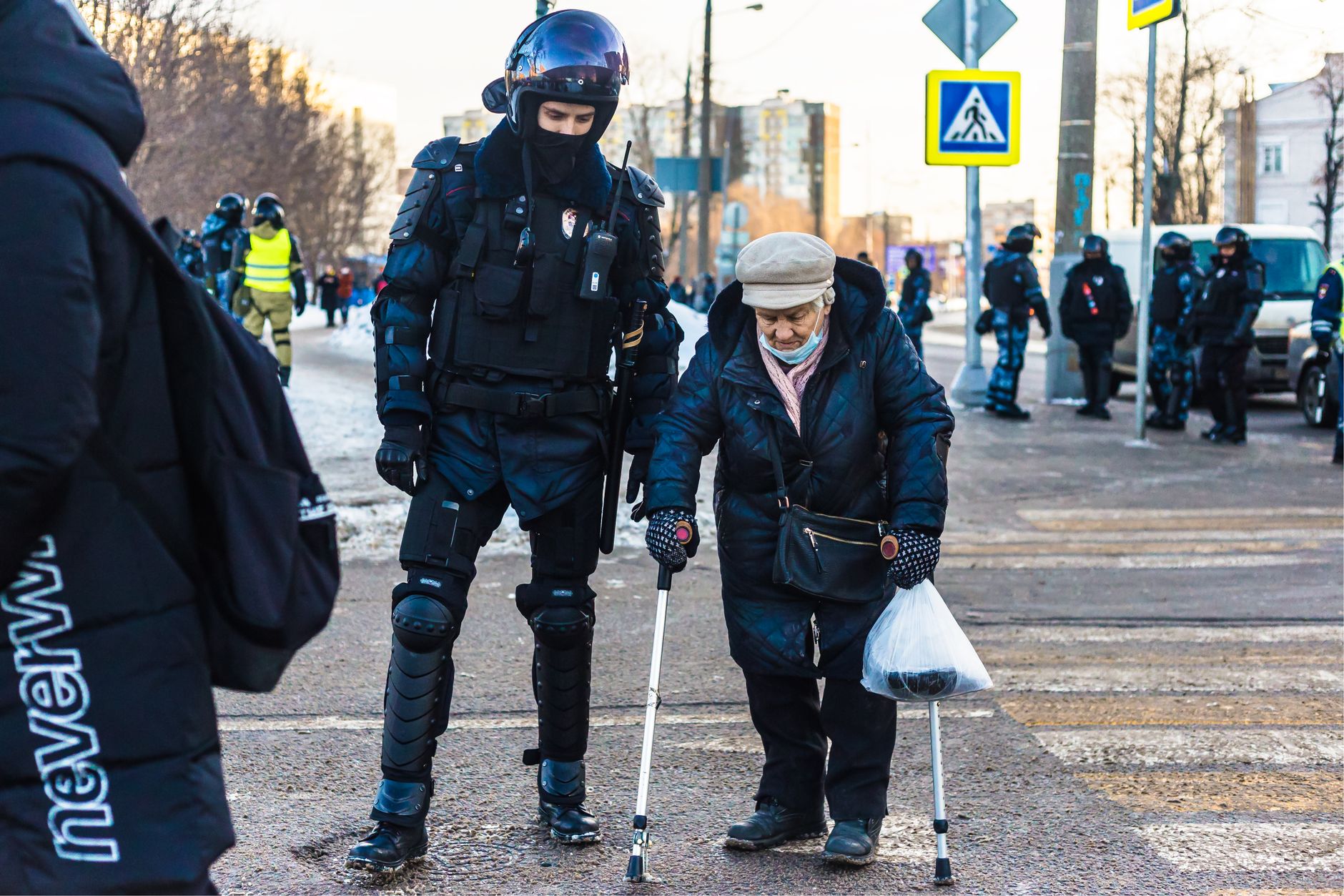 A police officer helps an elderly woman cross a street, showcasing human kindness and community service.