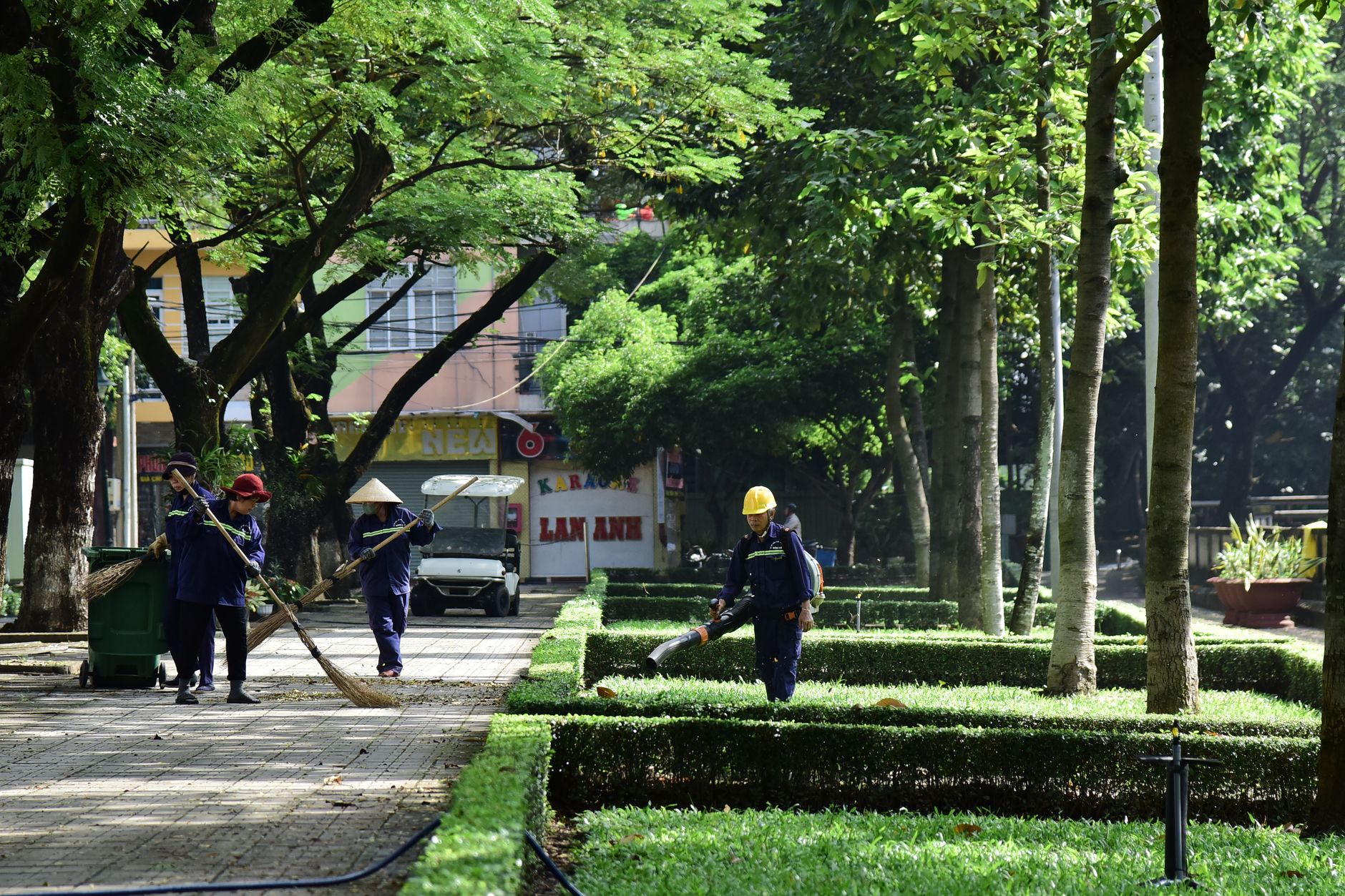 City park maintenance workers tending to greenery on a sunny day, creating a clean and serene environment.