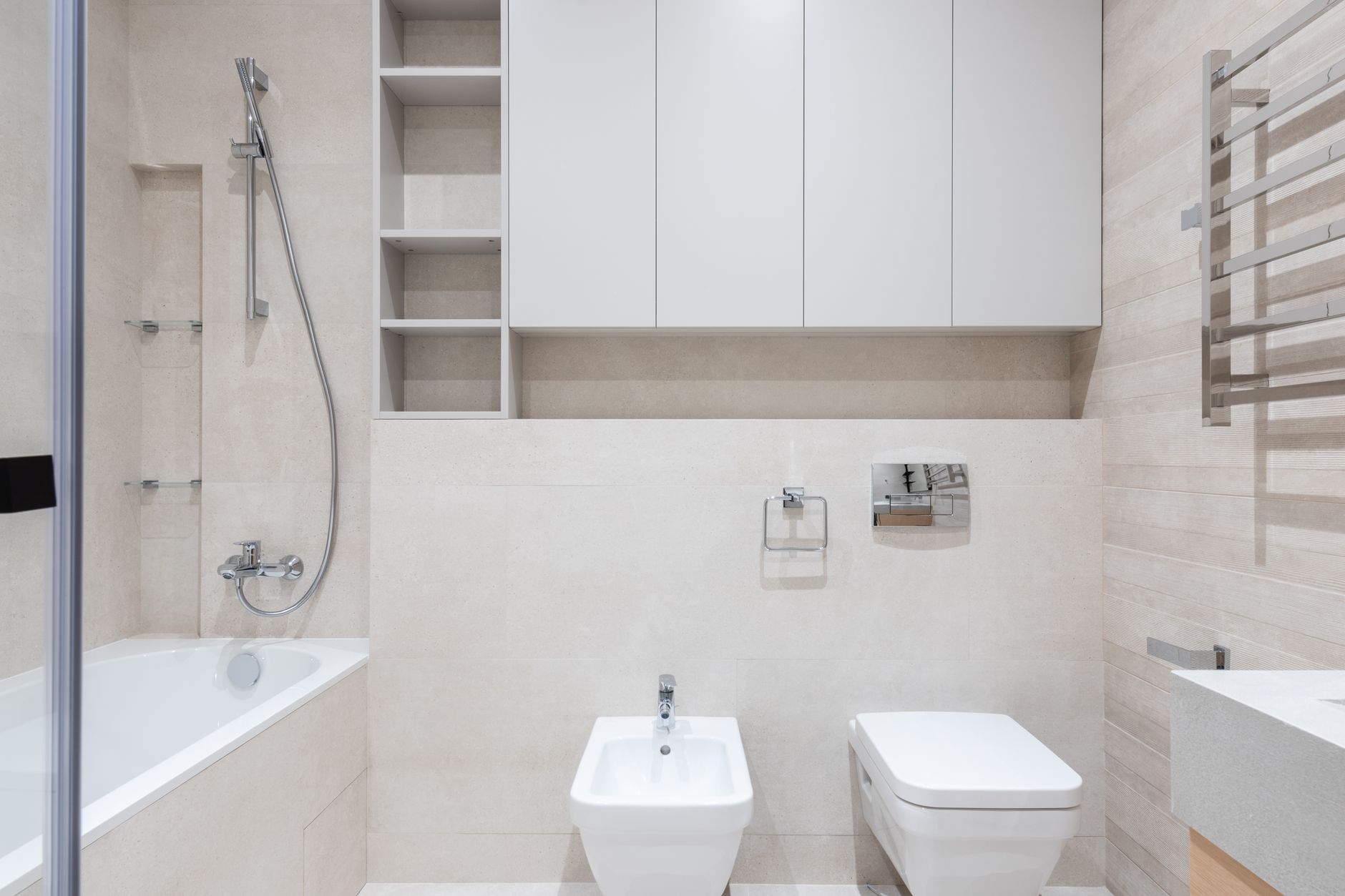 Interior of modern light bathroom with bidet and toilet next to sink and bath