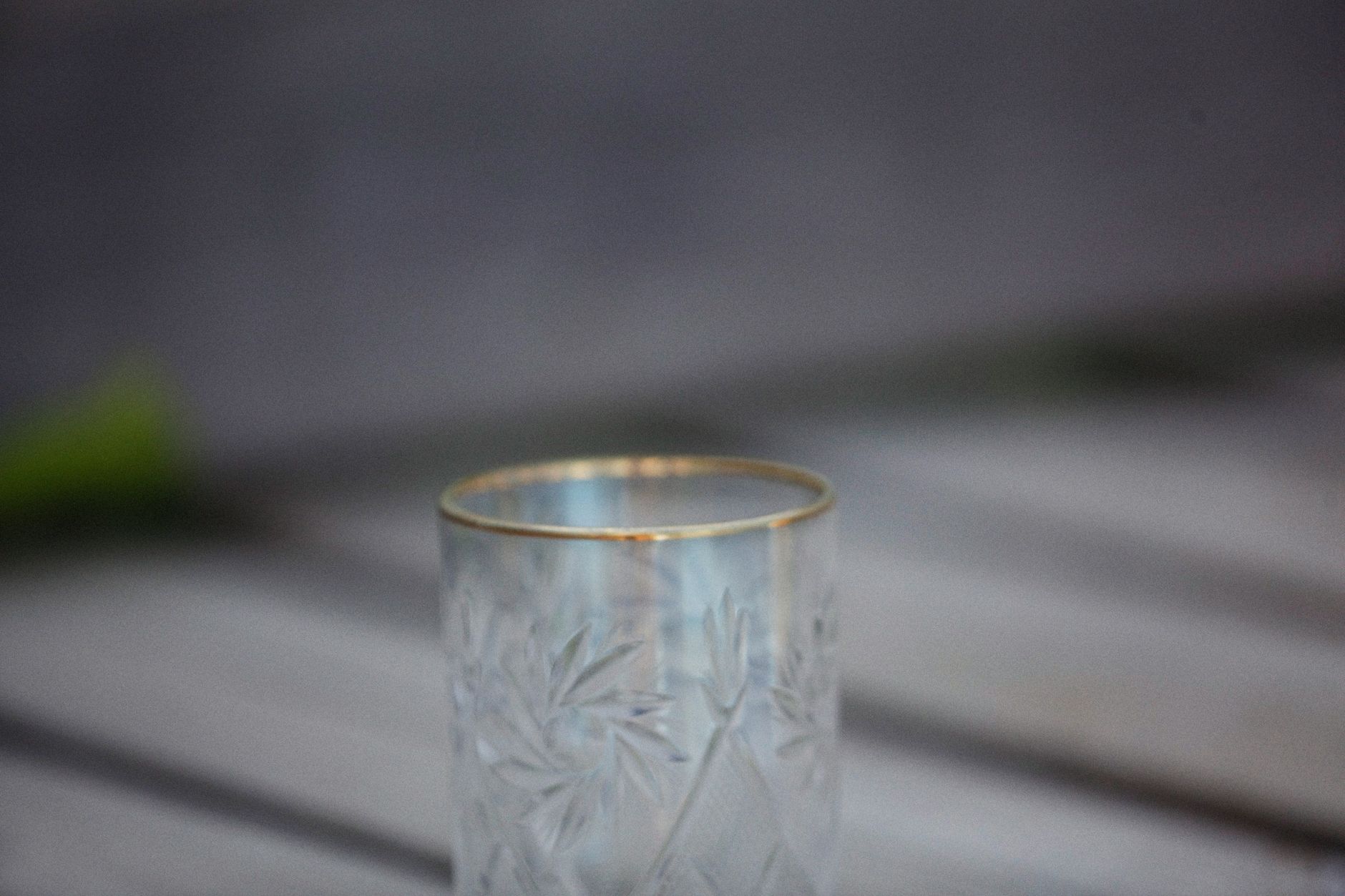 Close-up view of a decorative empty glass tumbler featuring intricate patterns and a sleek gold rim.