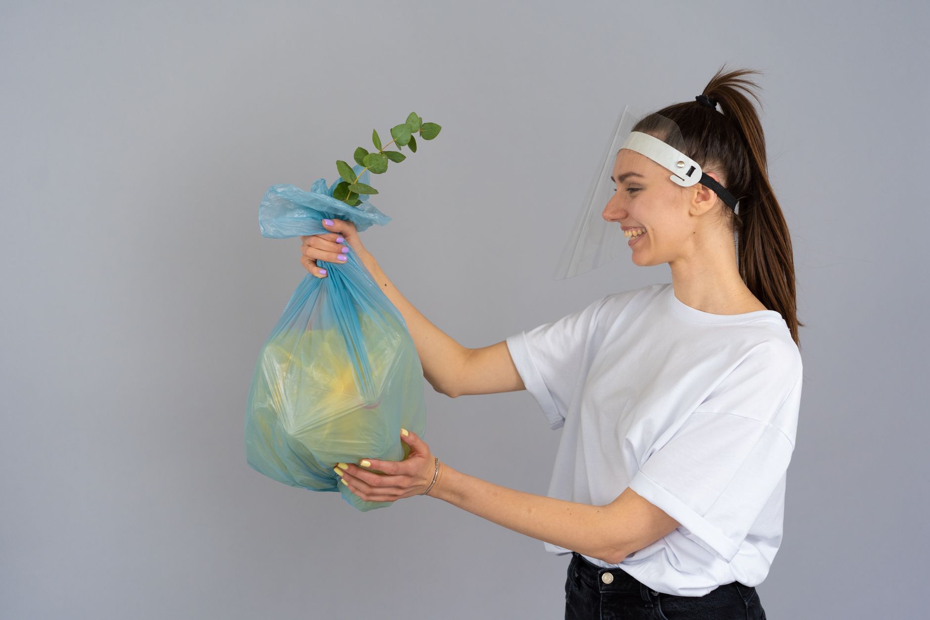 Smiling woman holding a recyclable bag with a plant, promoting eco-friendly practices.