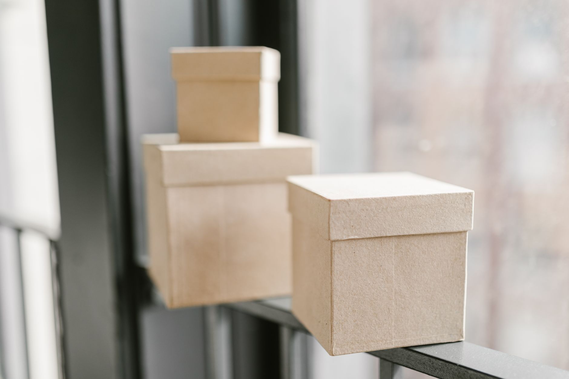 Simple cardboard boxes placed on a window sill with a blurred background.