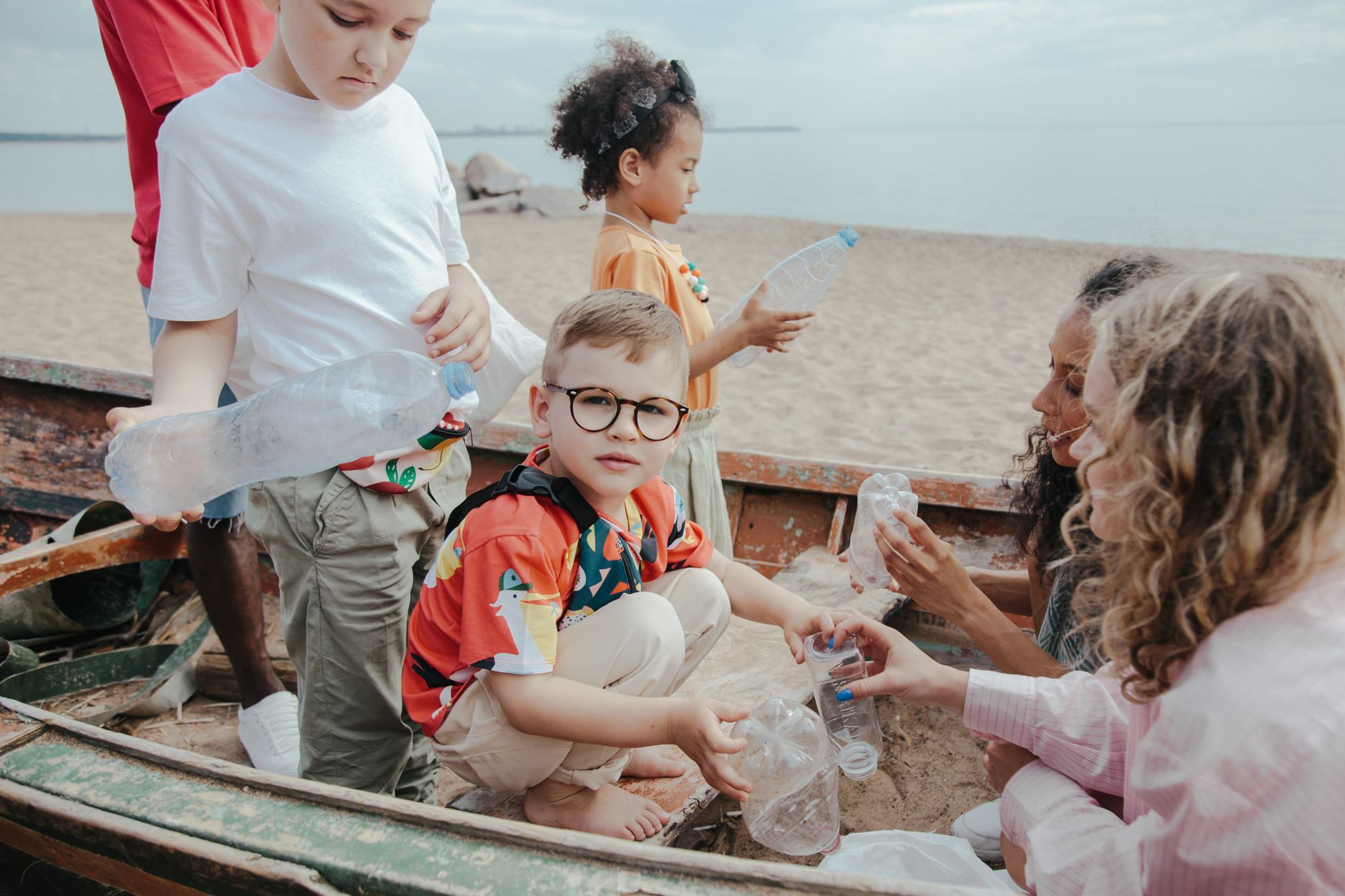 Children collect plastic on a beach, promoting environment protection.
