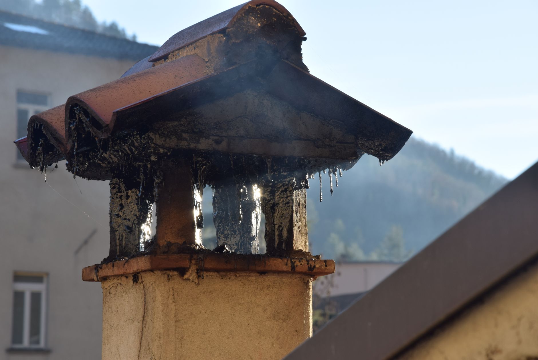 Close-up of a brick chimney stack releasing smoke, highlighting urban architecture.