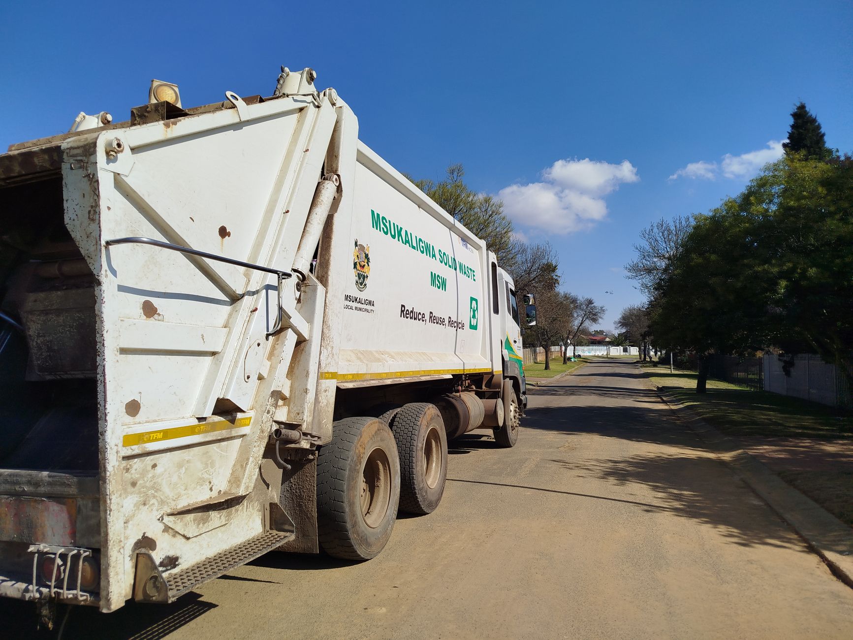 Garbage truck from Msukaligwa municipality collecting waste in a suburban area.
