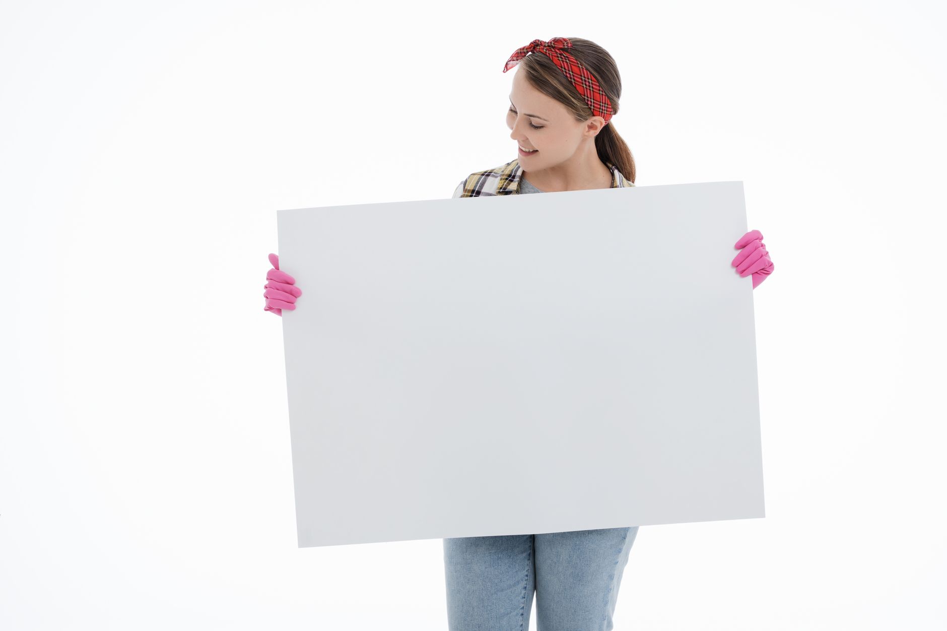 Young woman in a plaid shirt and gloves presenting a blank board with copyspace.