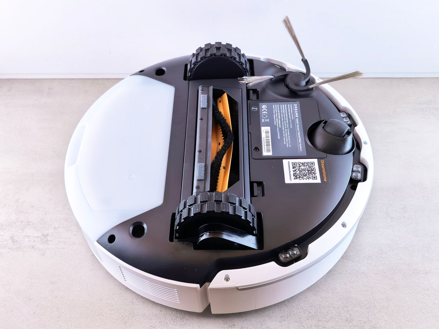 Close-up view of a robotic vacuum cleaner's underside displaying brushes and sensors.