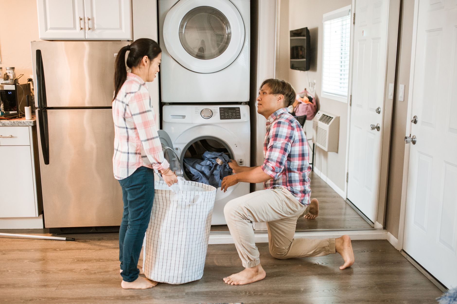 Couple managing household chores by doing laundry in a home setting.